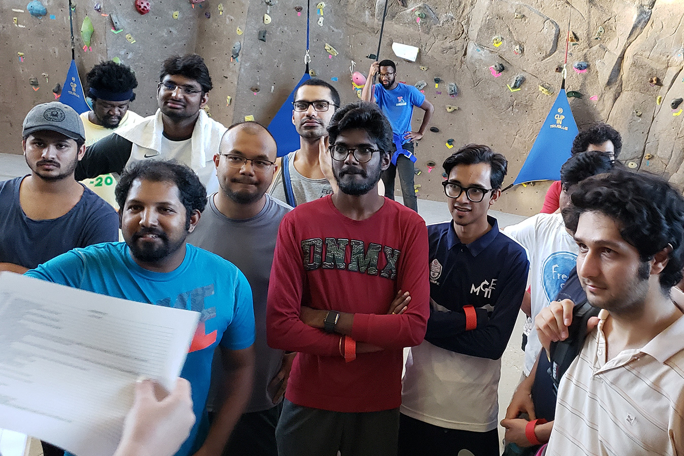 Graduate students gathered in front of a rock climbing wall