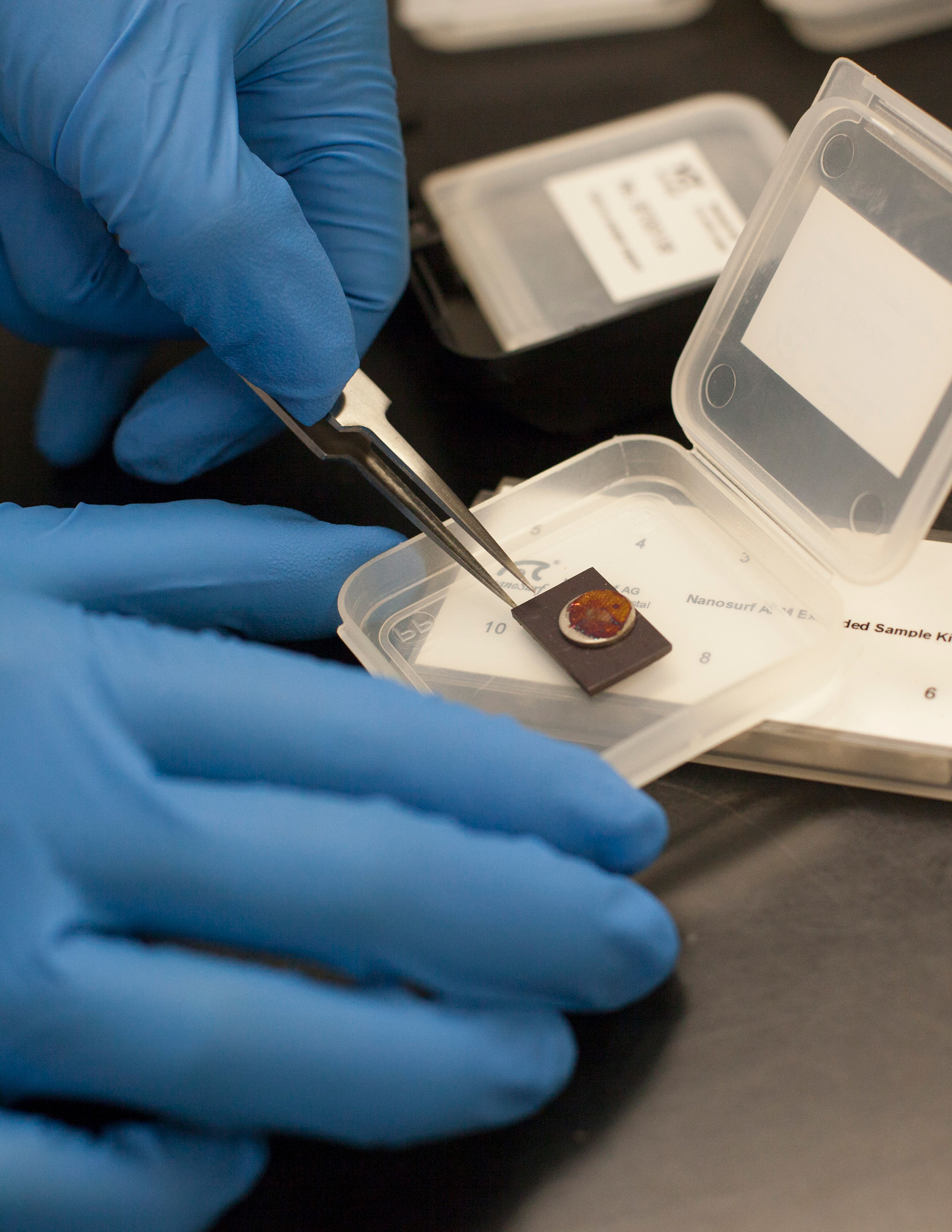 Gloved hands handling a nano device