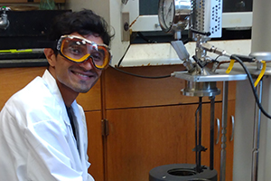 Vir Sagar, wearing a lab coat and safety glasses, smiling as he uses equipment in the Biomass Lab at Louisiana Tech University