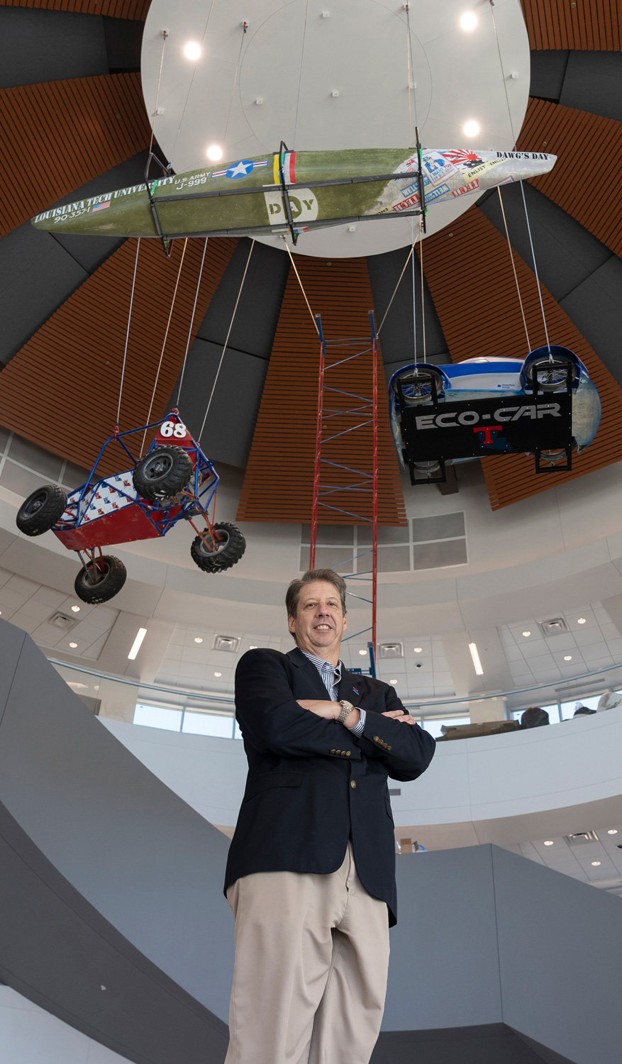 COES Dean Dr. Hisham Hegab standing under Baja, Eco-Car, and Concrete Canoe prototypes