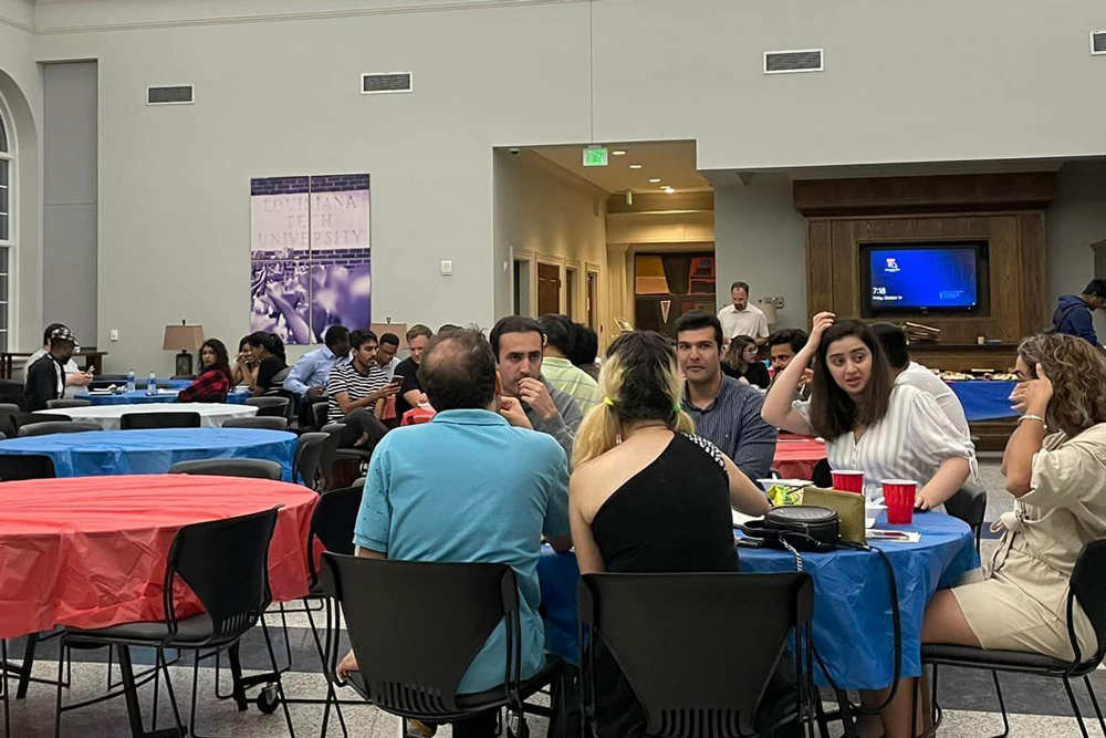 Graduate students at tables, enjoying a potluck meal